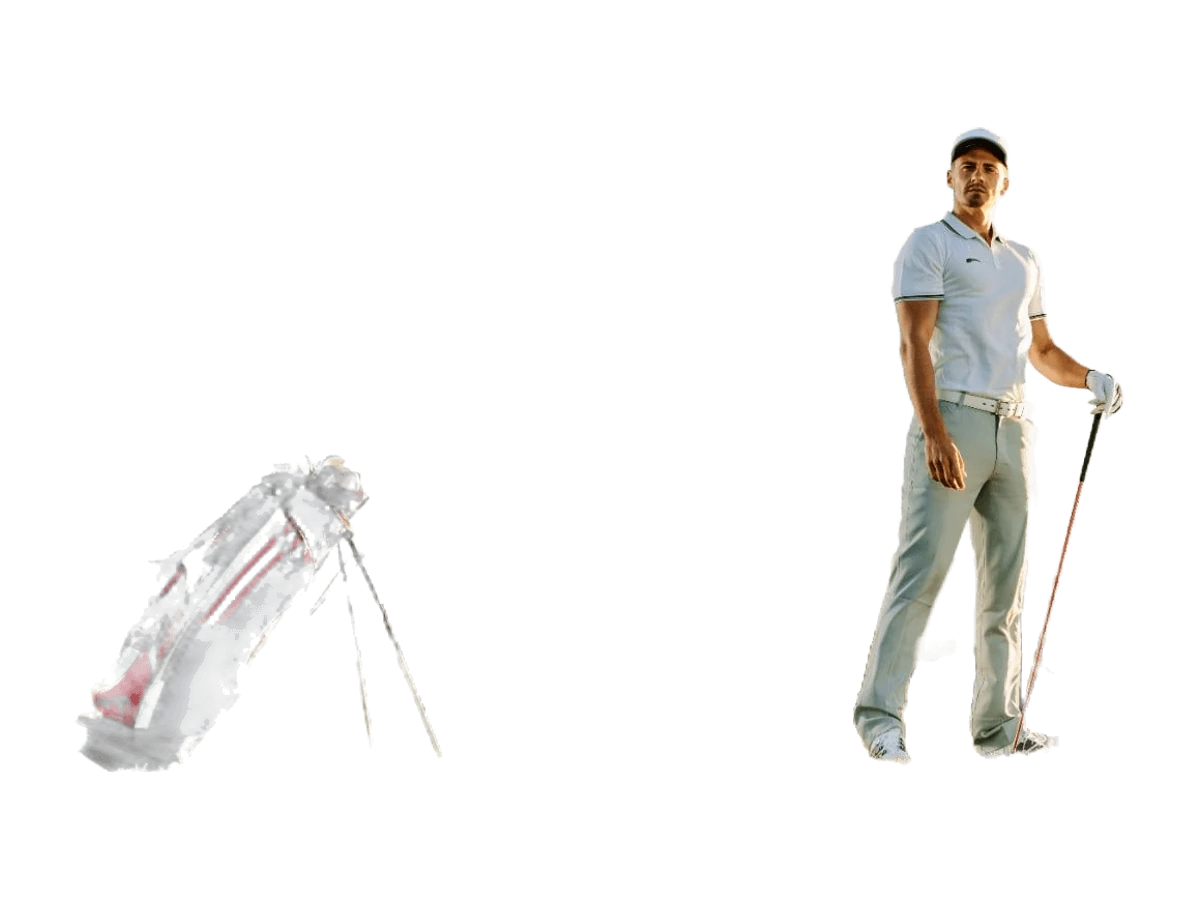 Golfer carrying a golf bag on a course at sunset.